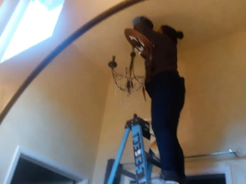 Electrician installing a chandelier in a Cleburne residence